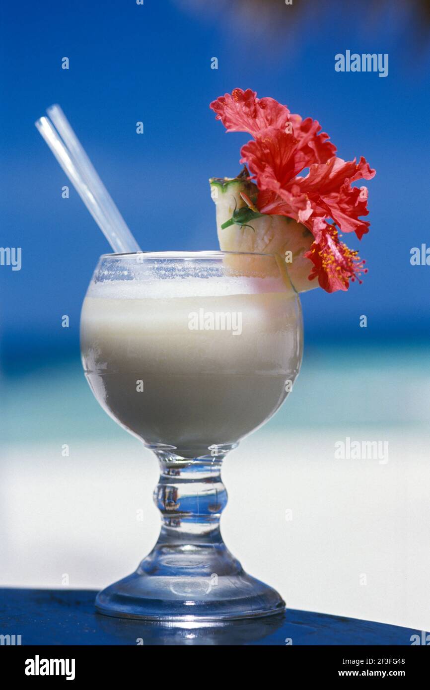 Pina Colada tropical drink with flower and fruit garnish at beach Stock Photo