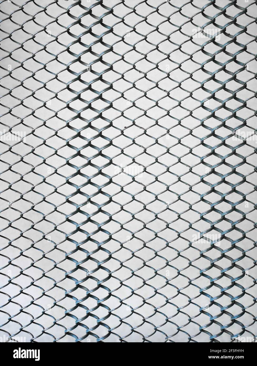 Metal springy mesh with chain link on a beige background, part of an old steel mattress with iron linked elements, close-up, vertical Stock Photo