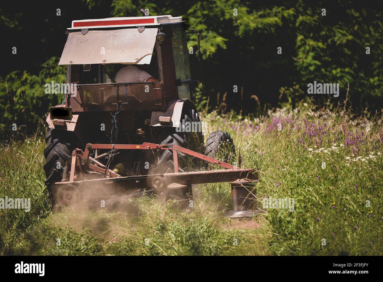 An industrial tractor cutting grass on a field Stock Photo Alamy
