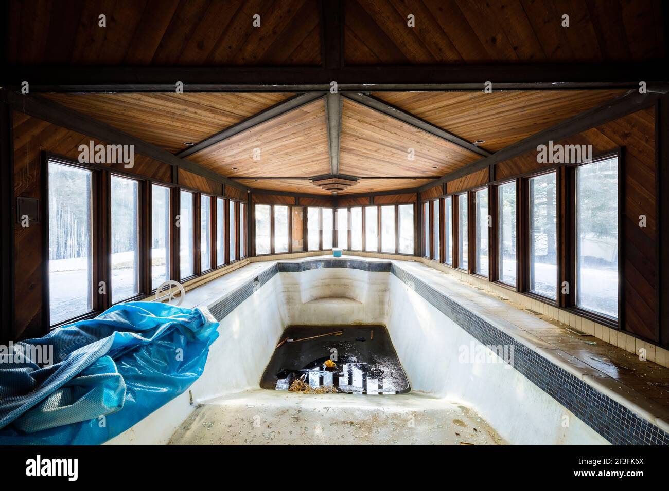A dirty indoor swimming pool inside of an abandoned mansion Stock Photo