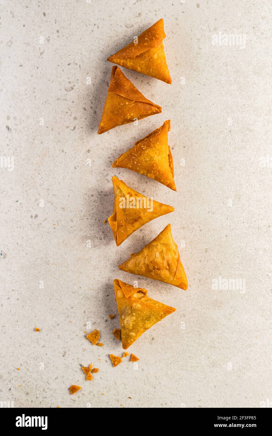 Samosa triangles placed in a pattern on a light surface Stock Photo