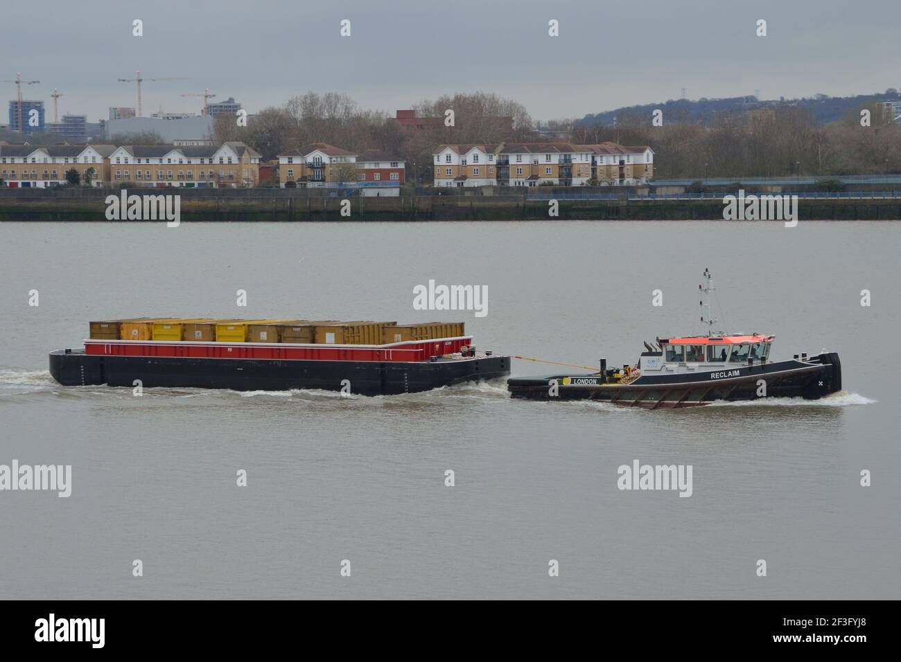 Cory Riverside Energy tug RECLAIM heading up the Thames in London towing brand new refuse barge called TEES Stock Photo