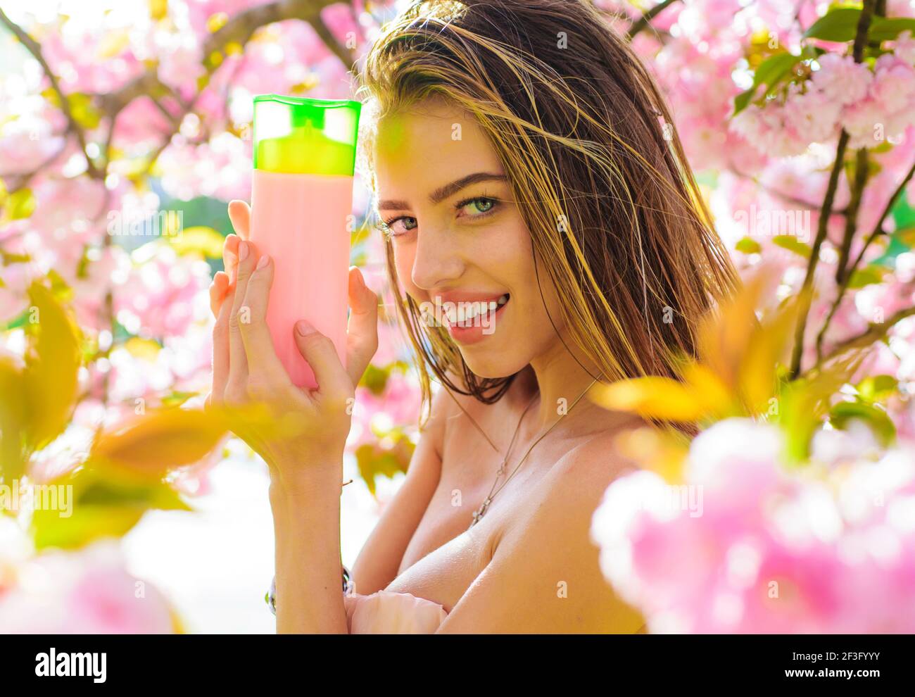 Smiling Woman with Shampoo. Beautiful girl with balsam or conditioner. Haircare. Stock Photo