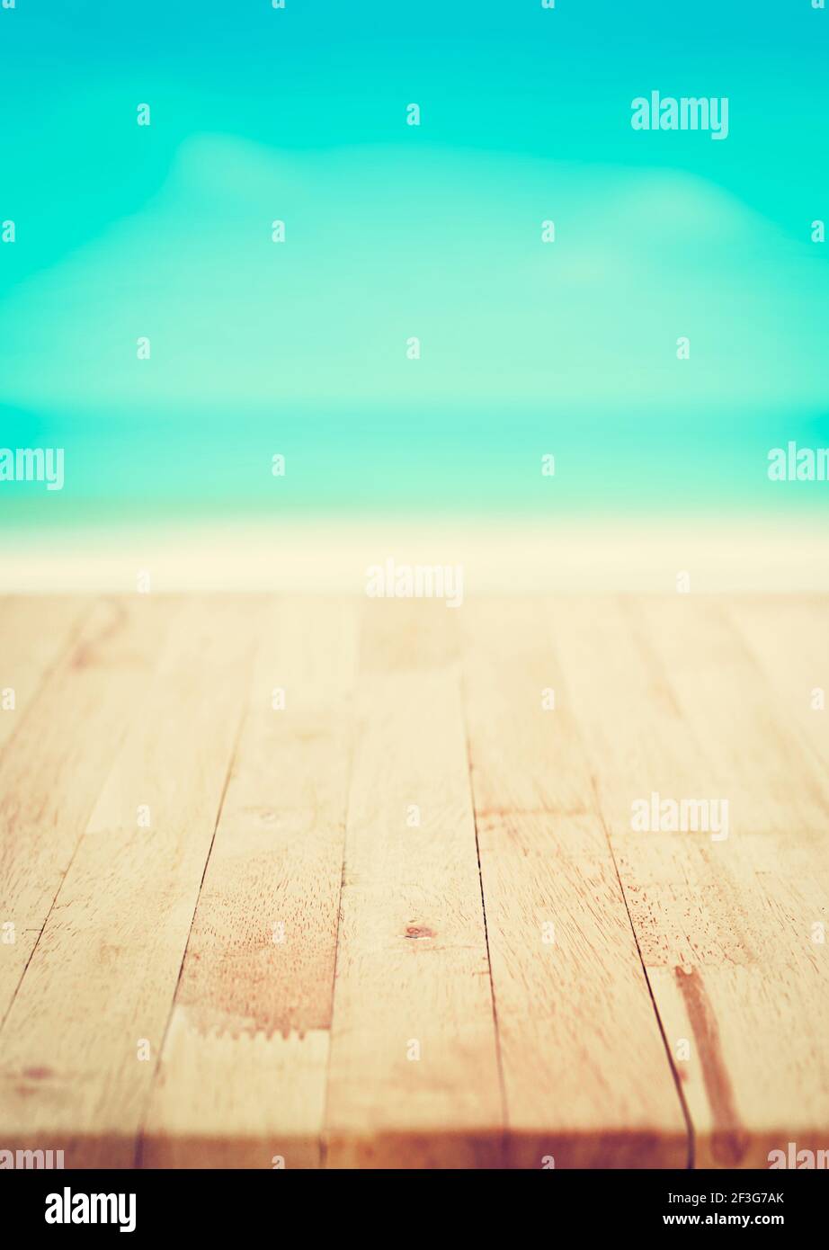 Wood table top on blur blue sea and white sand beach background, summer concept, vintage tone - poster size proportion Stock Photo