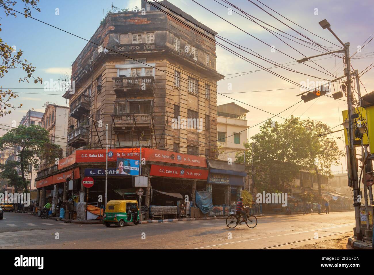 Old city road at sunrise with view of old buildings with an auto rickshaw waiting for commuters at Chandni Chowk area of Kolkata India Stock Photo