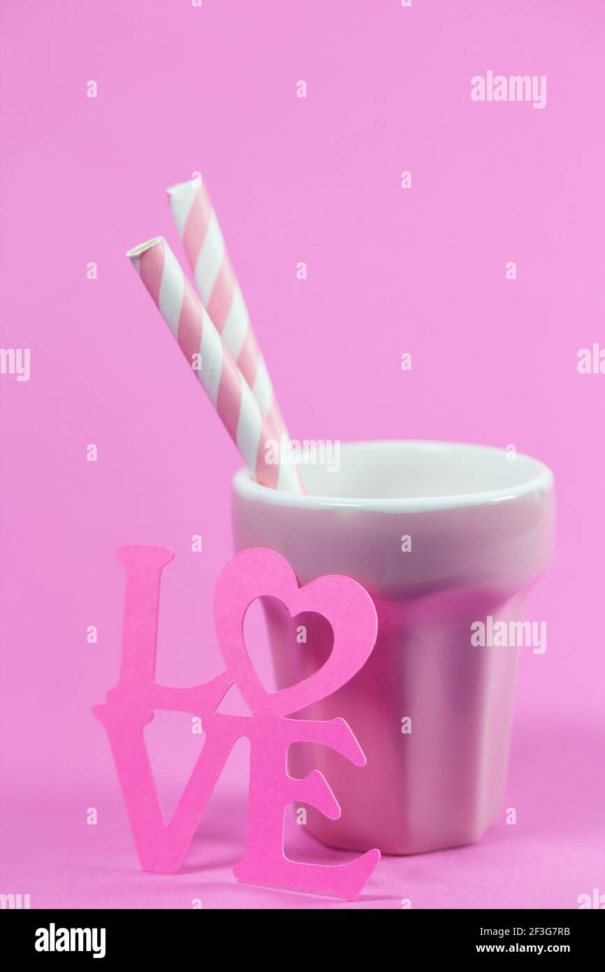 Two straws in a pink glass for lovers. Stock Photo