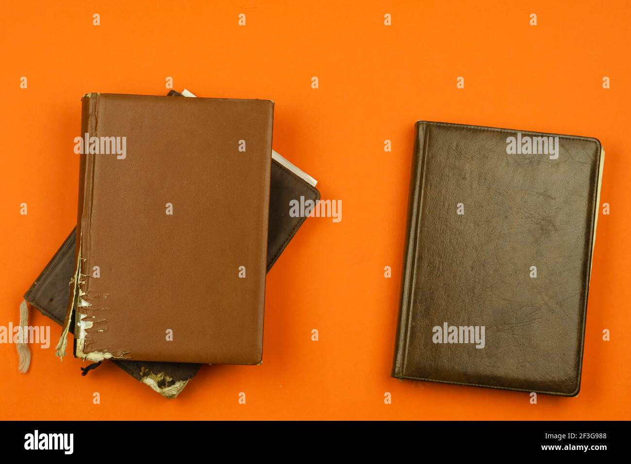 Old Tattered diaries on red background. Three closed Diaries in brown and black tattered cover with no lettering. Flat lay, copy space Stock Photo