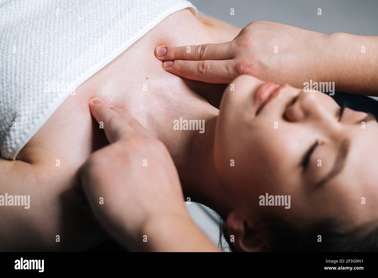 Close-up top view of young woman lying down on massage table during shoulder and neck massage Stock Photo