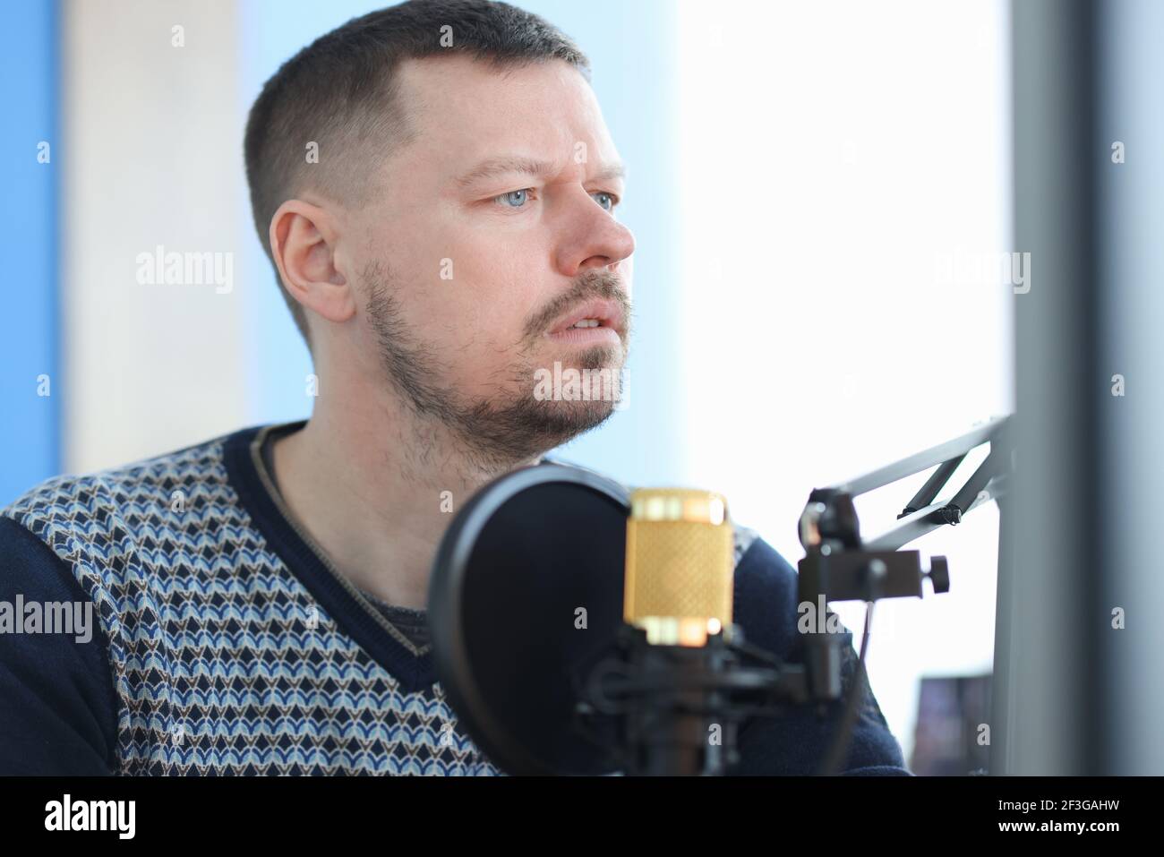 Young man sitting in front of microphone in recording studio Stock Photo