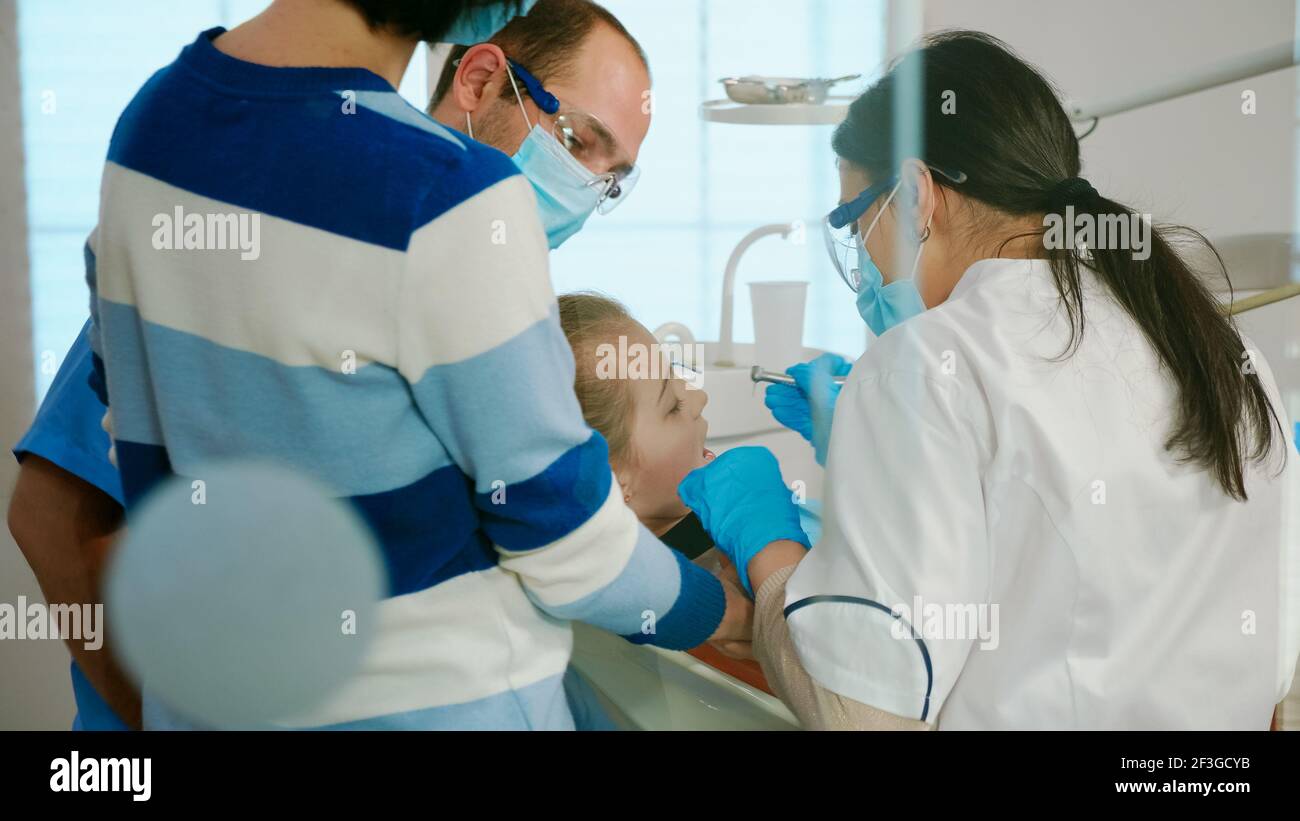 Dentists with gloves and mask removes tooth decay drilling teeth during