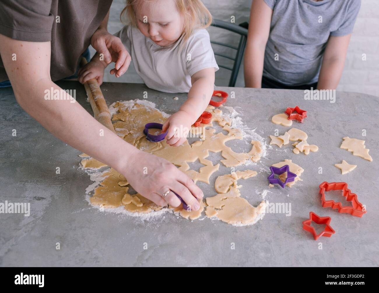 mom helps the children cut out beautiful cookie shapes from the dough. top view Stock Photo