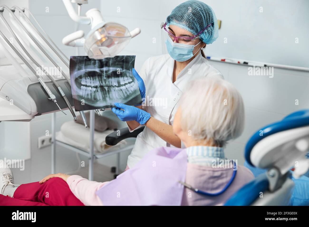 Dentist introducing dental x-ray to a female in medical chair Stock Photo