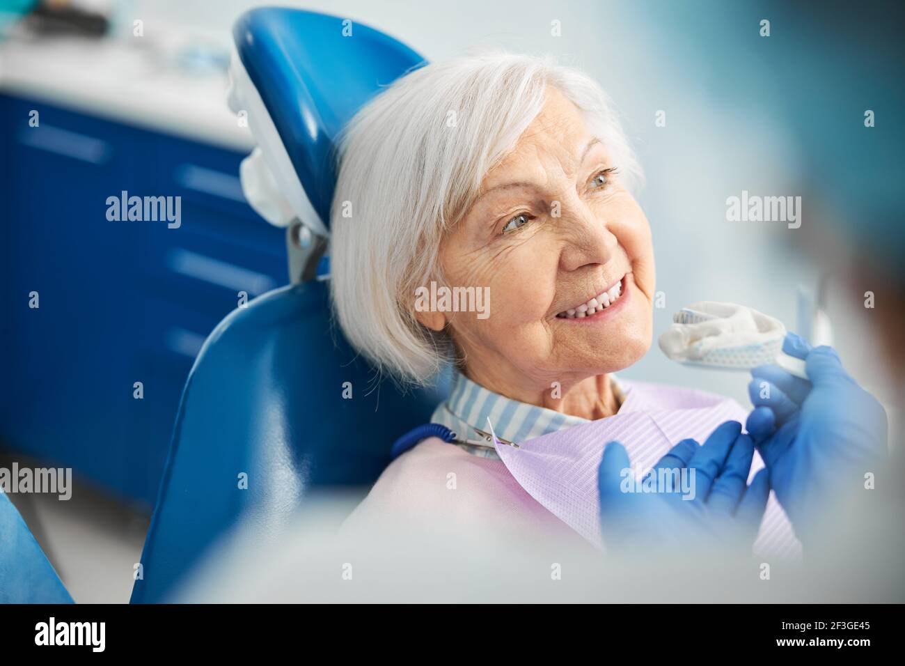 Glad senior female receiving a suggestion of silicone dental impression Stock Photo