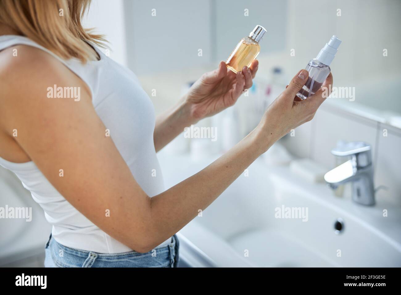 Young woman holding skincare products in bathroom Stock Photo Alamy