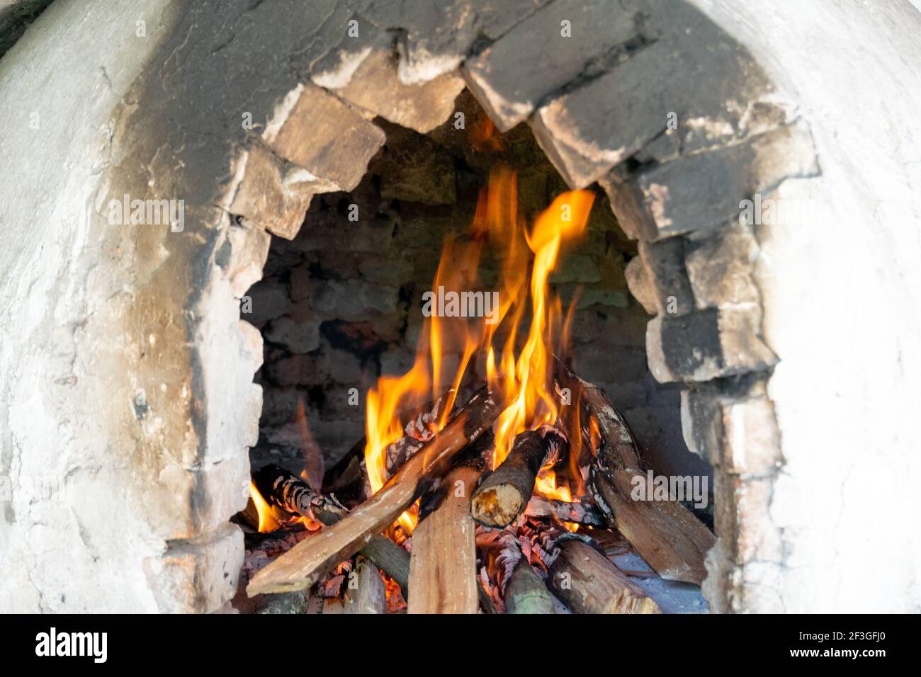 A selective focus of burning firewoods inside an old brick fireplace Stock Photo
