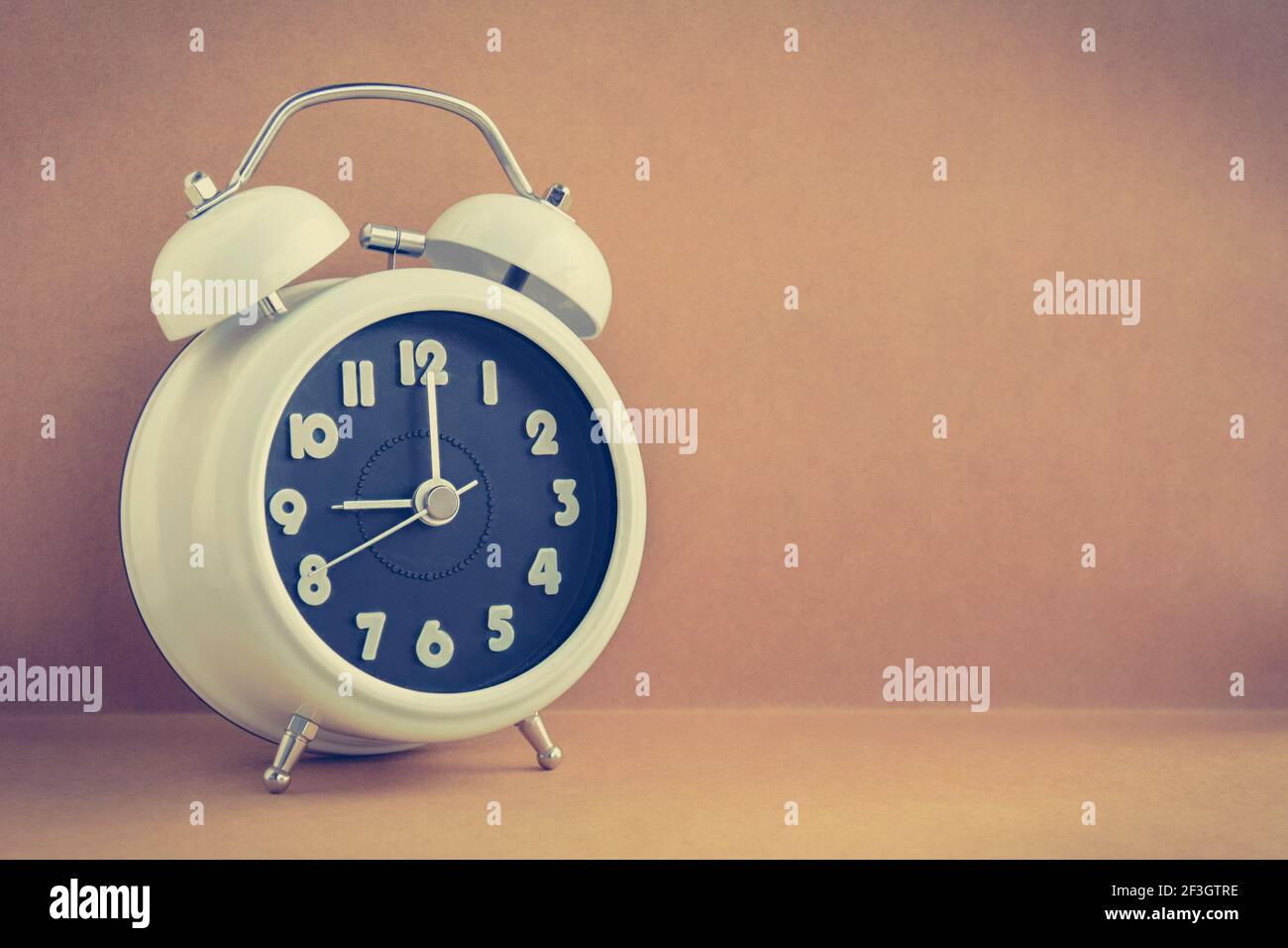 Retro alarm clock on brown background with copy space - vintage tone Stock Photo