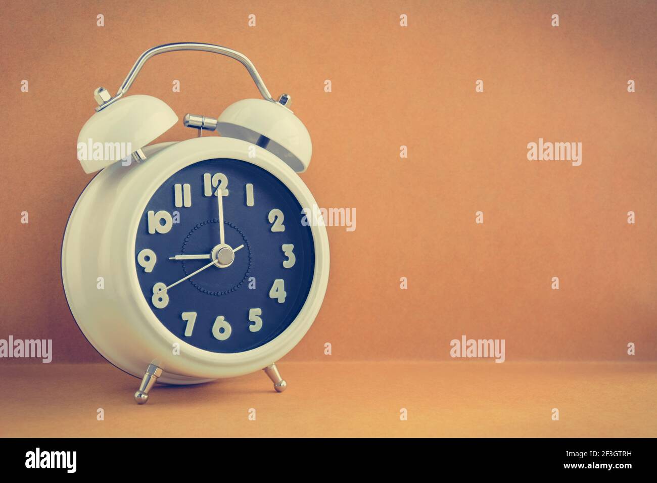 White retro alarm clock on light brown background with copy space