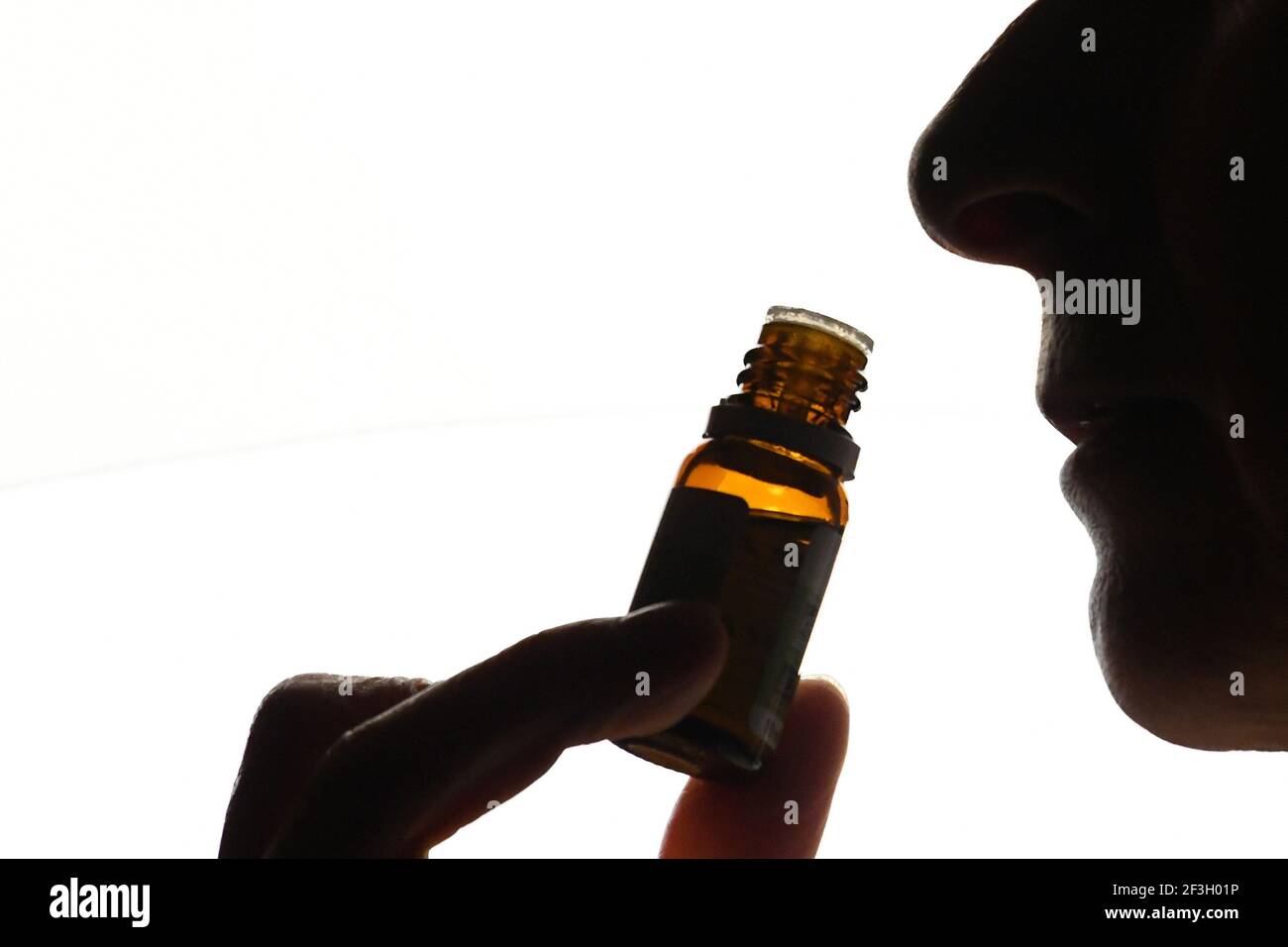 Olfactory test. Close-up shot, silhouette of someone smelling a flask ...