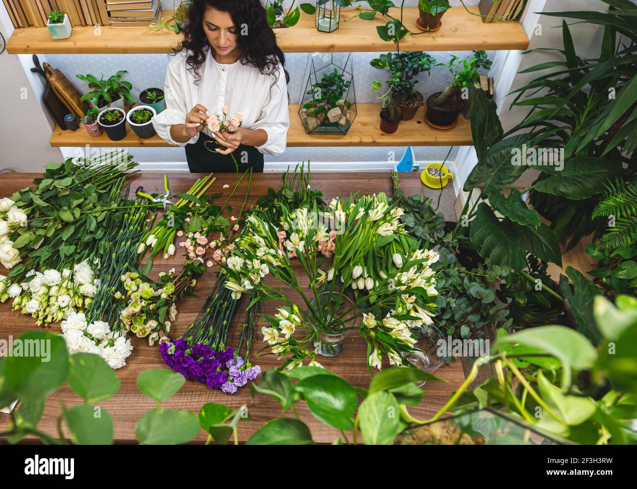 Attractive young woman florist is working in a flower shop Stock Photo ...