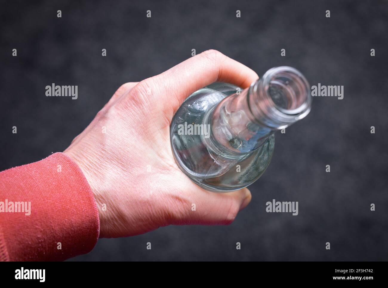 A man's hand holding a bottle of vodka. The problem of alcoholism in