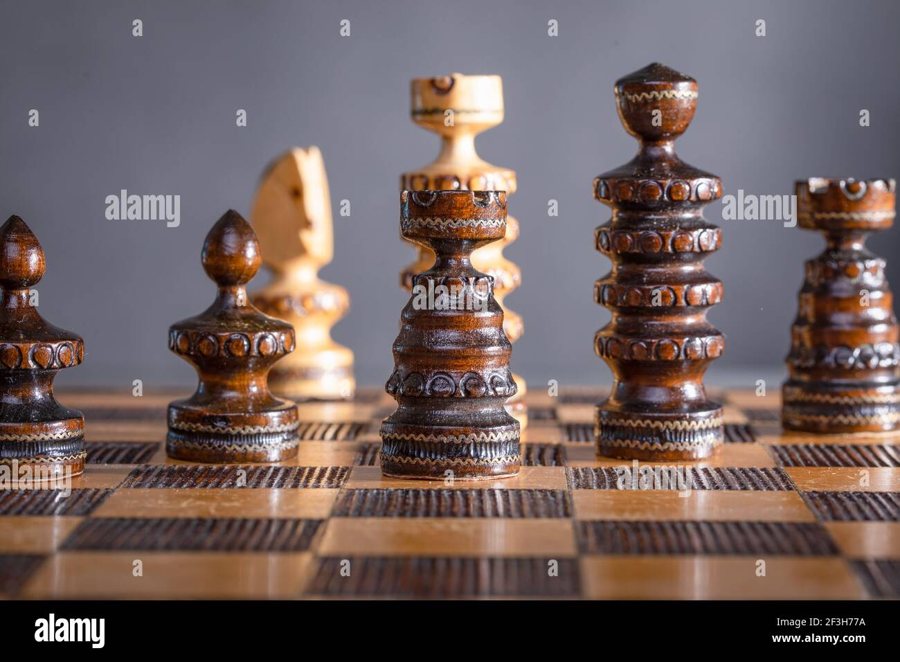 Wooden chess pieces set up on a chessboard losing or winning the