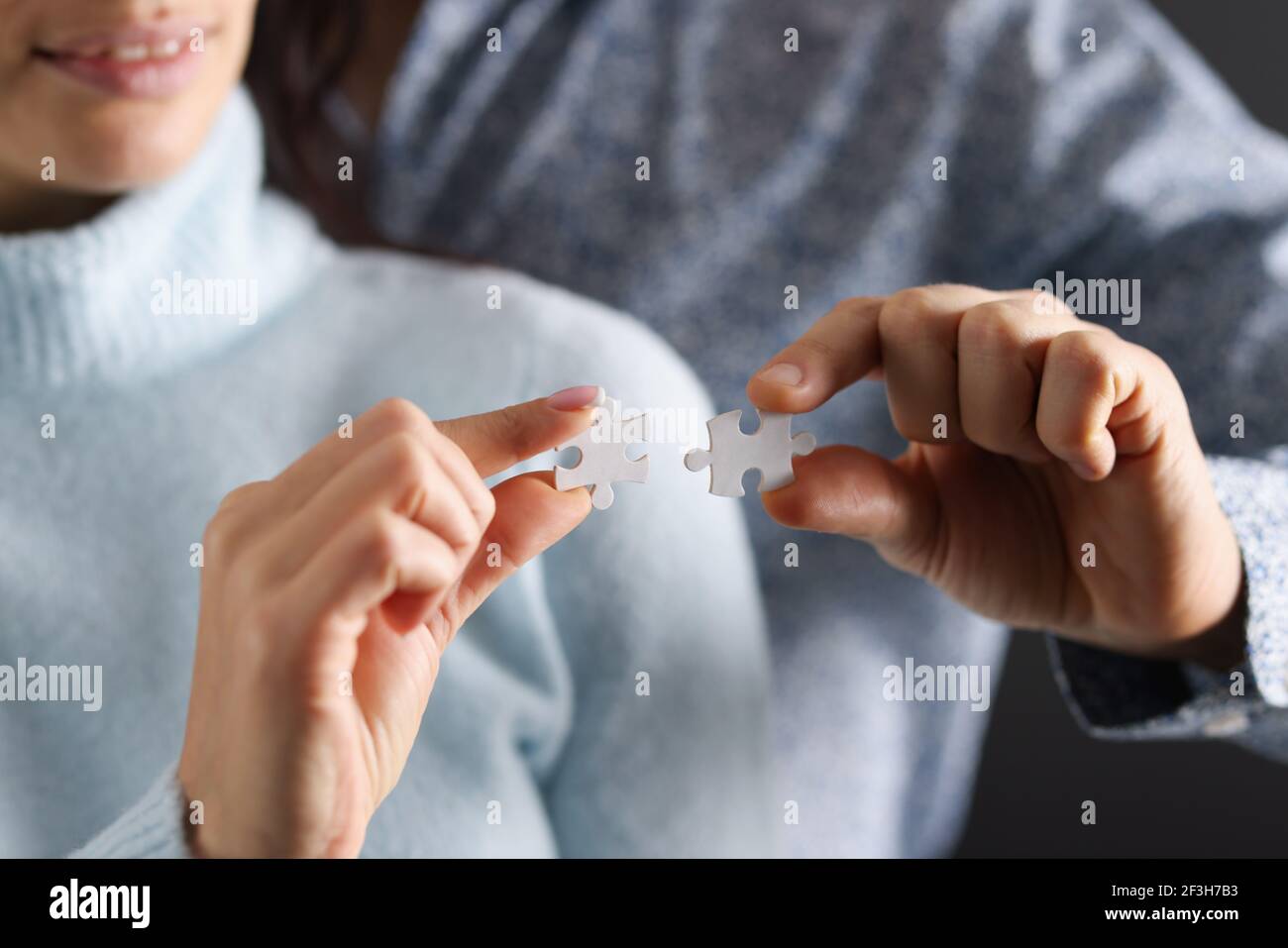 Man and woman are trying to connect white puzzles together Stock Photo