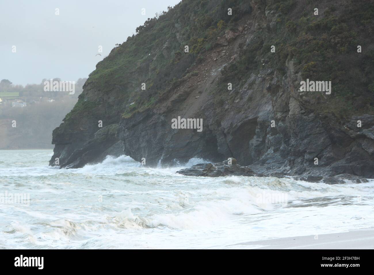 Atlantic storm waves crashing up and washing over rocks and sand on the Carlyon bay beach in Cornwall on the south west coast of England Stock Photo