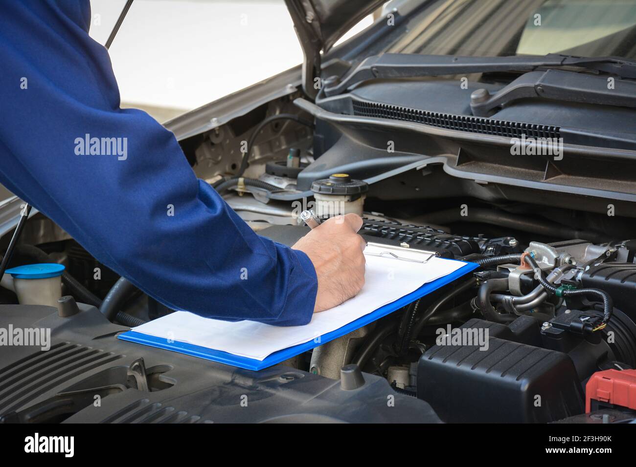 Auto mechanic (or technician) checking car engine at the garage Stock Photo