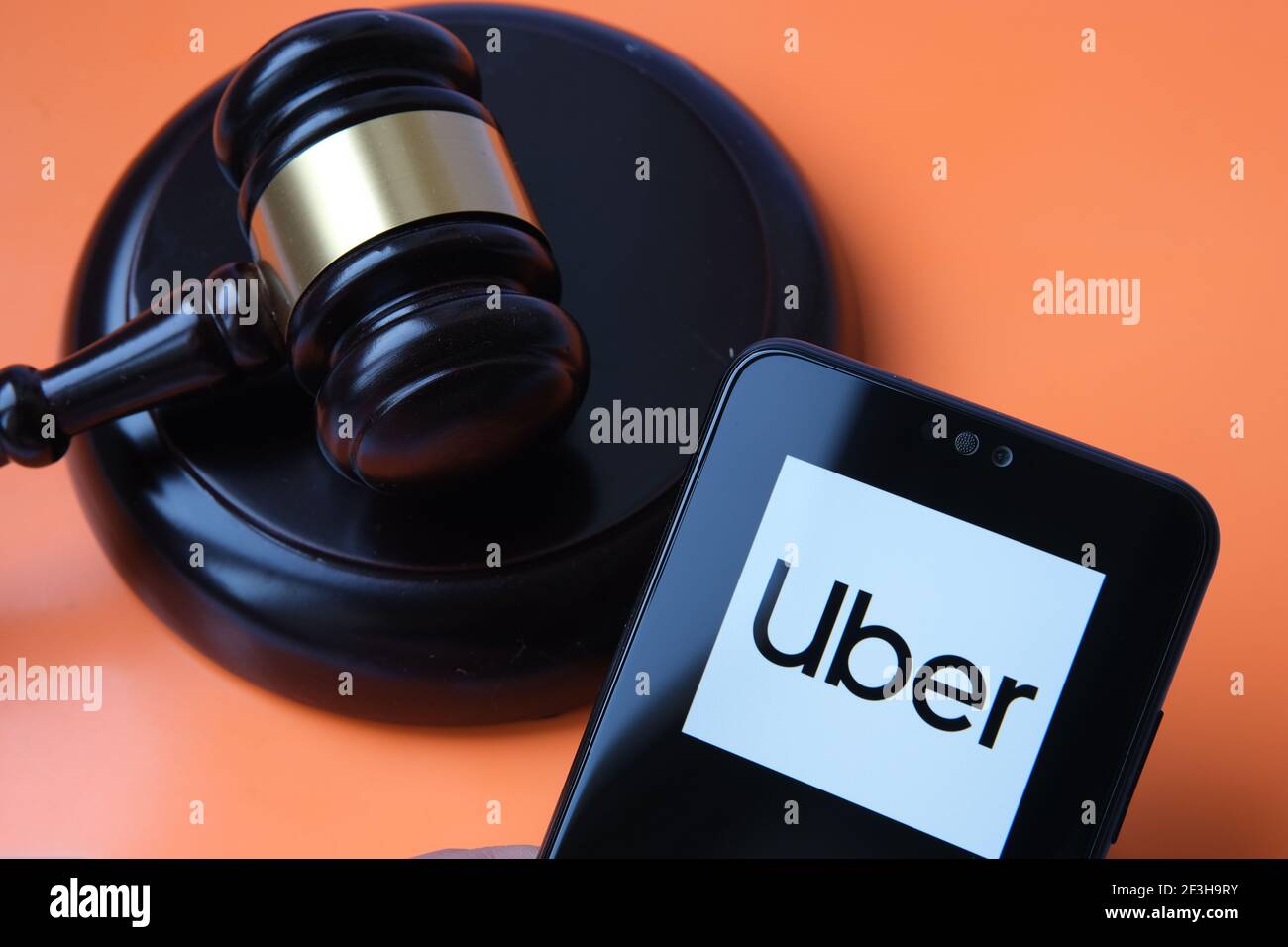 Uber logo seen on smartphone and judge gavel on the blurred background. Concept for court ruling, Uber driver rights by Supreme court. Stafford, Unite Stock Photo