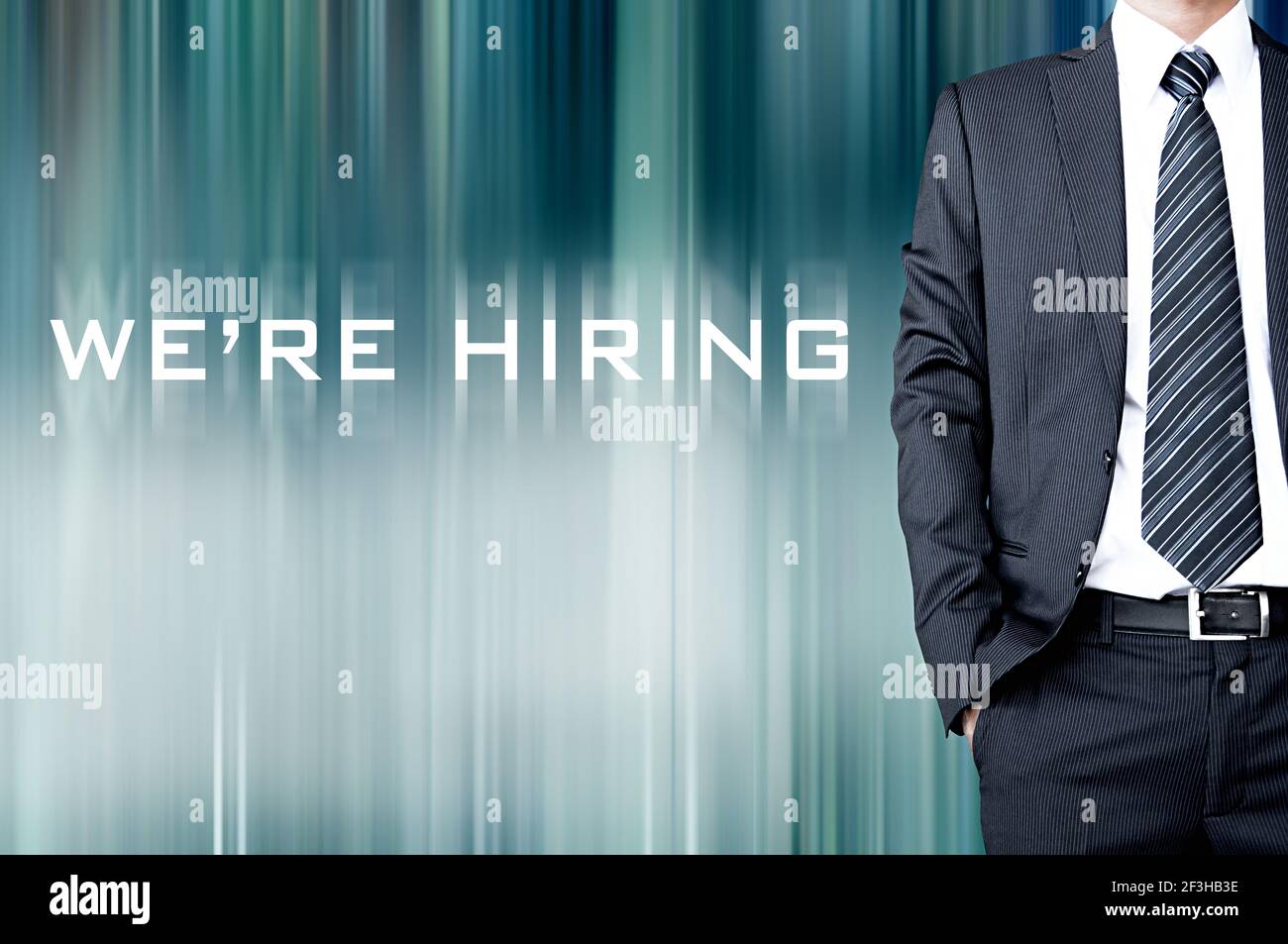 WE'RE HIRING sign on blur background with standing businessman Stock Photo