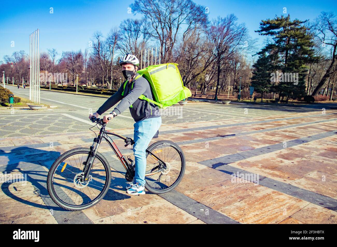 Delivery man riding bike wearing mask Stock Photo