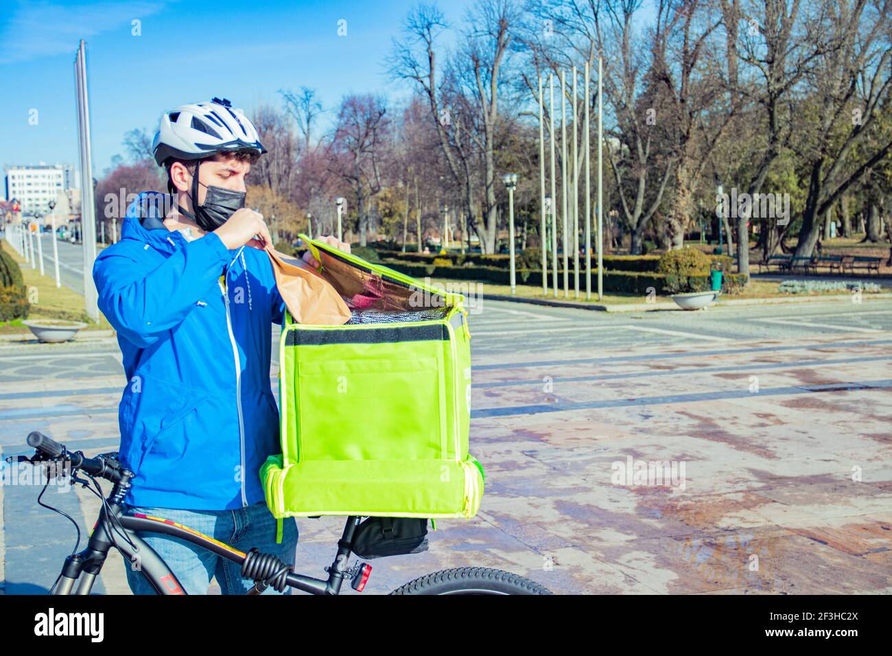 Delivery man riding bike wearing mask Stock Photo