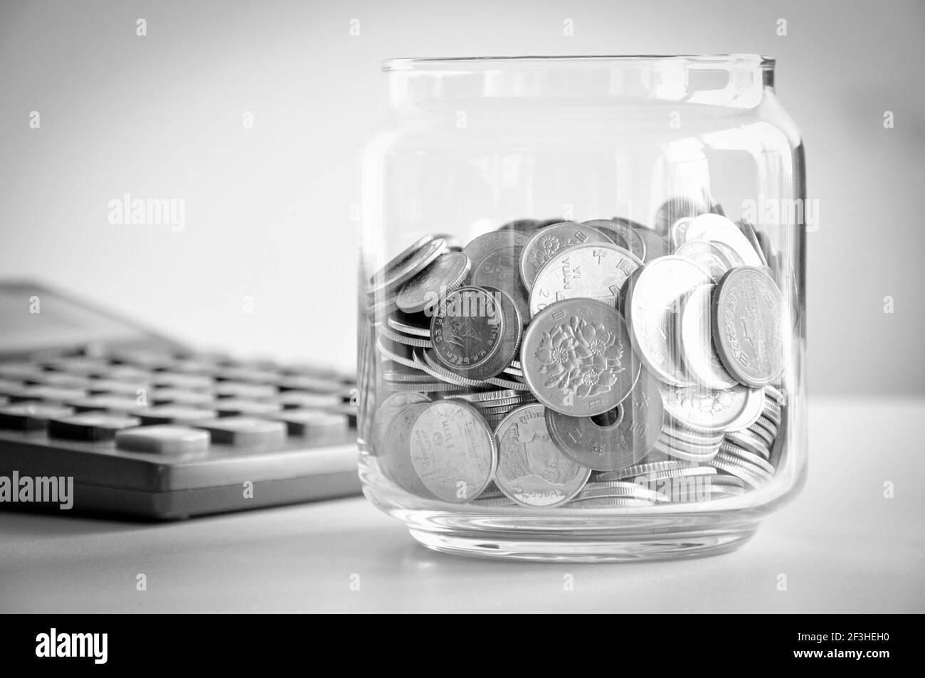 Coins in the glass jar, mixed Asian multi currencies - monochrome effect Stock Photo