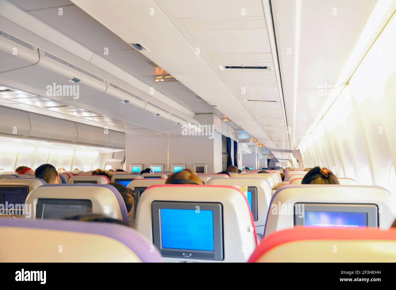 Airplane seats in the cabin with personal TV on board - economy or coach  class Stock Photo - Alamy