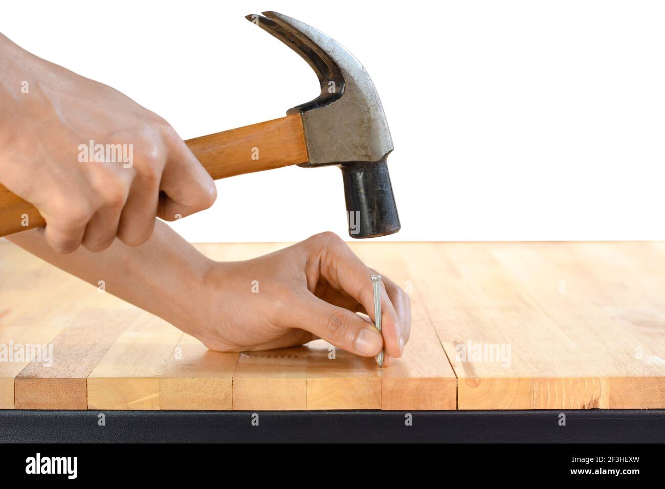 Hand hammering a nail on wood table top Stock Photo