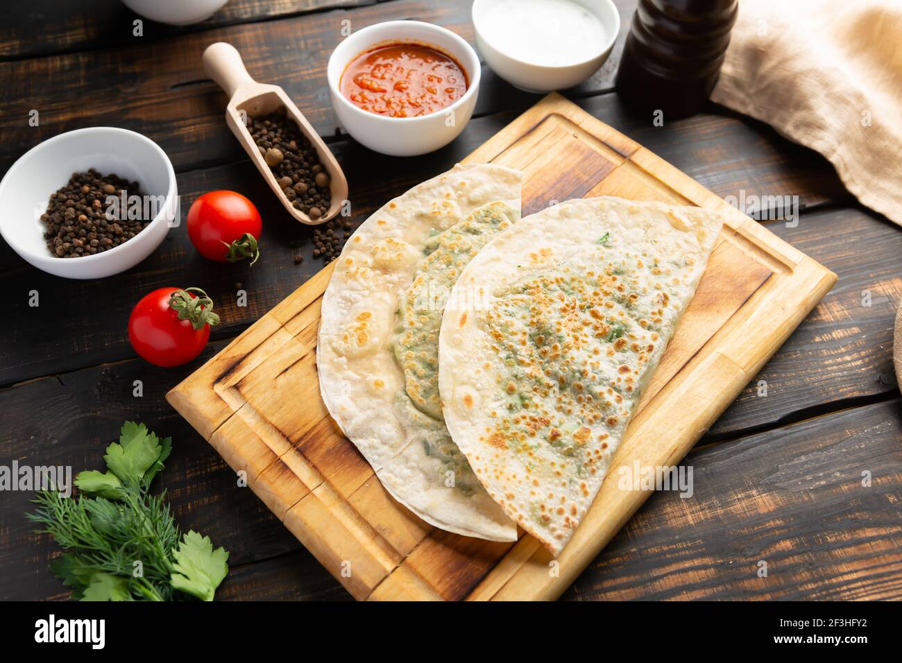 Azerbaijani national dish gutab with meat and vegetables together with yoghurt and sumac on wooden table Stock Photo