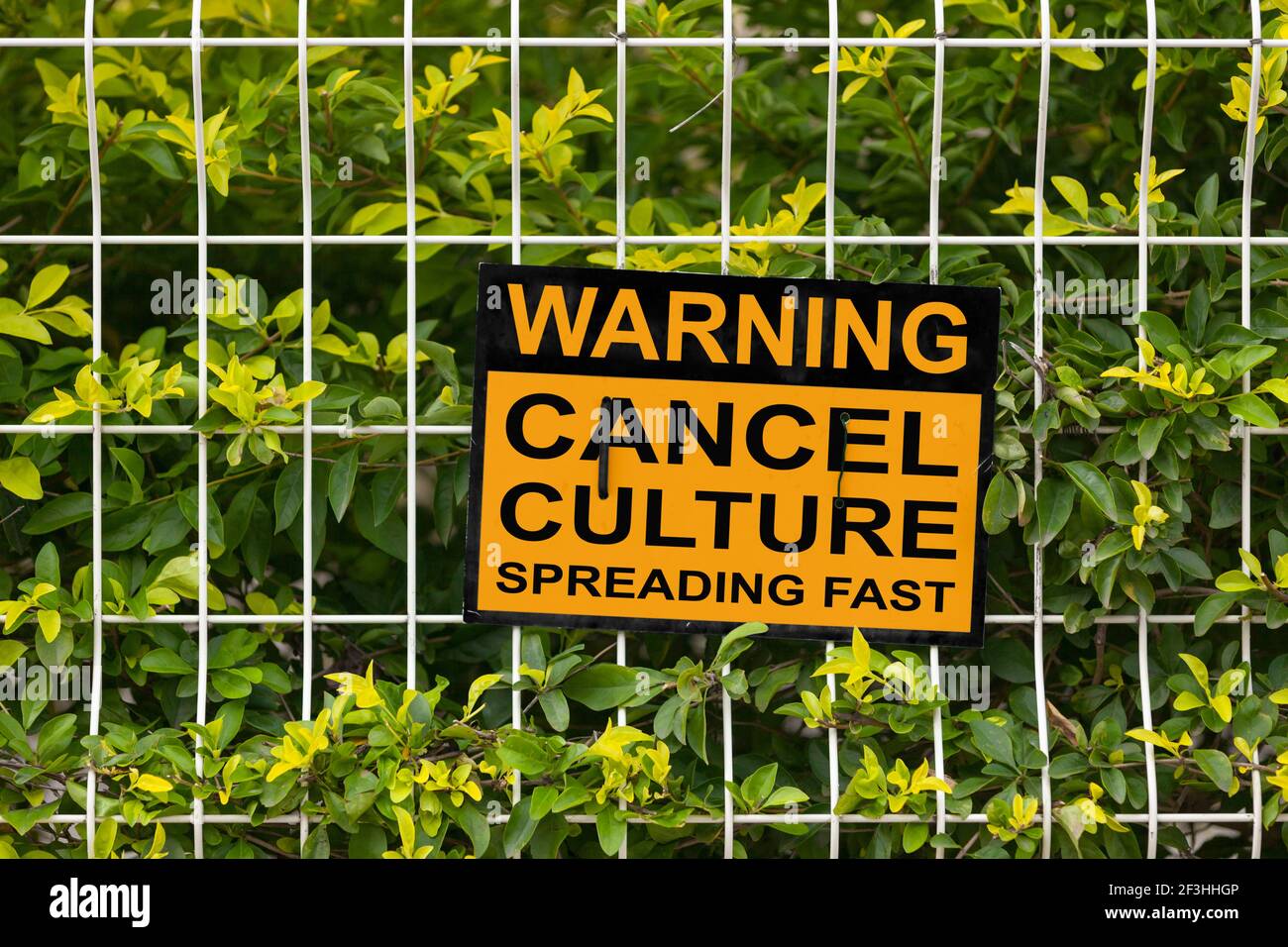 Black and yellow warning sign on a fence stating 'Warning, cancel culture spreading fast'. Stock Photo