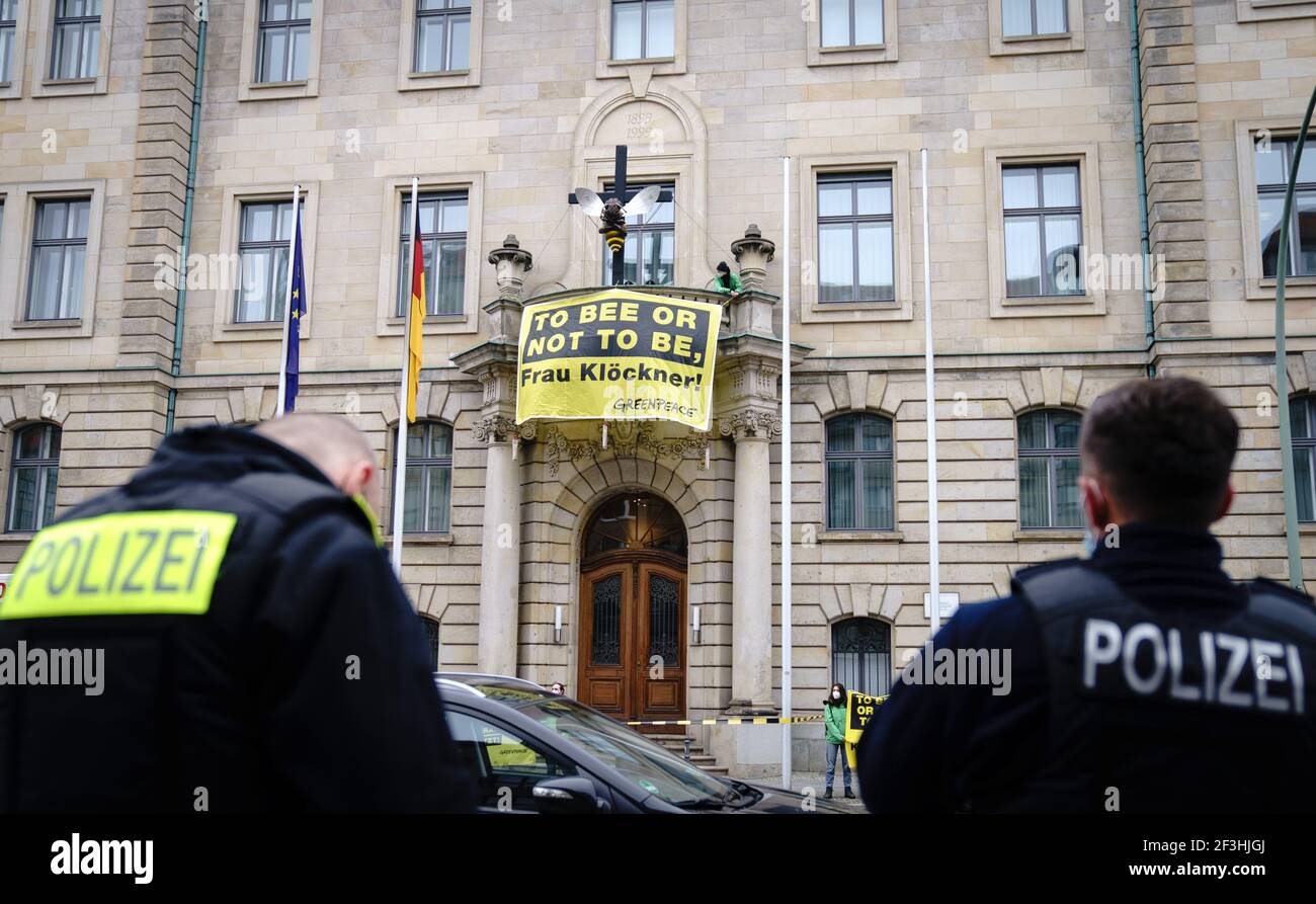 Berlin, Germany. 17th Mar, 2021. Greenpeace activists display a poster with the play on words 'To bee or not to be, Frau Klöckner' in front of their sculpture of a bee on a cross on the balcony of the Federal Ministry of Agriculture, while police officers stand in the street below. With this, the environmentalists protest for the preservation of diversity in the fields and demand more funding for the protection of species. Credit: Kay Nietfeld/dpa/Alamy Live News Stock Photo