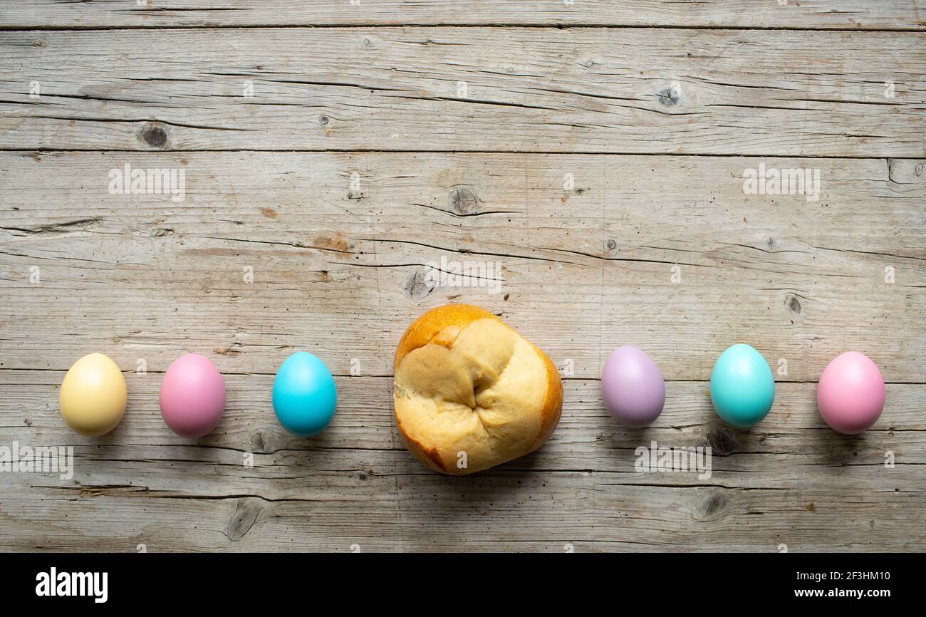 small easter bread pinze with some colorful easter eggs on wooden background Stock Photo