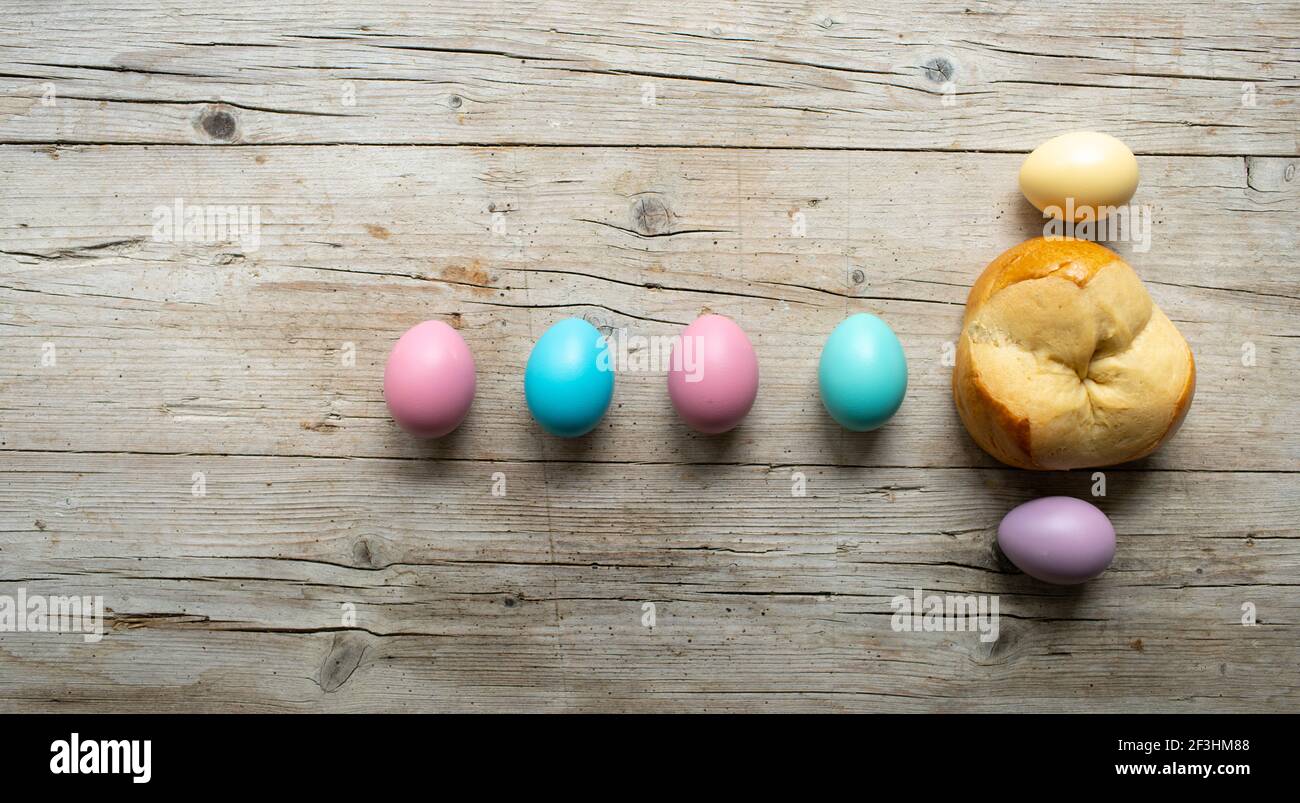 small easter bread pinze with some colorful easter eggs on wooden background Stock Photo