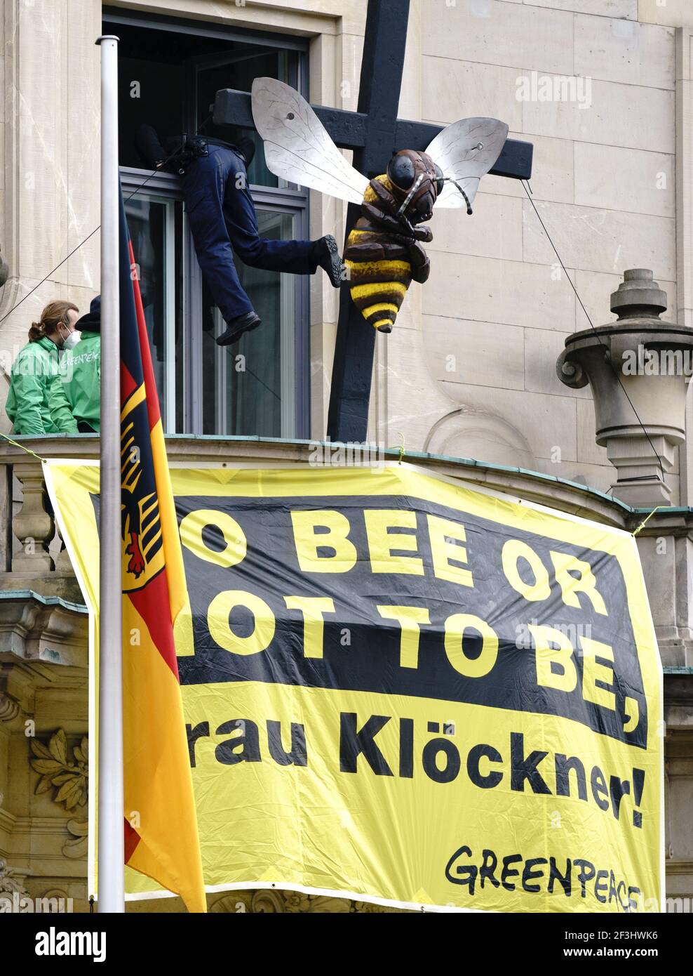 Berlin, Germany. 17th Mar, 2021. Greenpeace activists display a poster with the play on words 'To bee or not to be, Frau Klöckner' in front of their sculpture of a bee on a cross on the balcony of the Federal Ministry of Agriculture, while a police officer climbs onto the balcony through an upper window. With this action, the environmentalists protest for the preservation of diversity in the fields and demand more funding for species protection. Credit: Kay Nietfeld/dpa/Alamy Live News Stock Photo