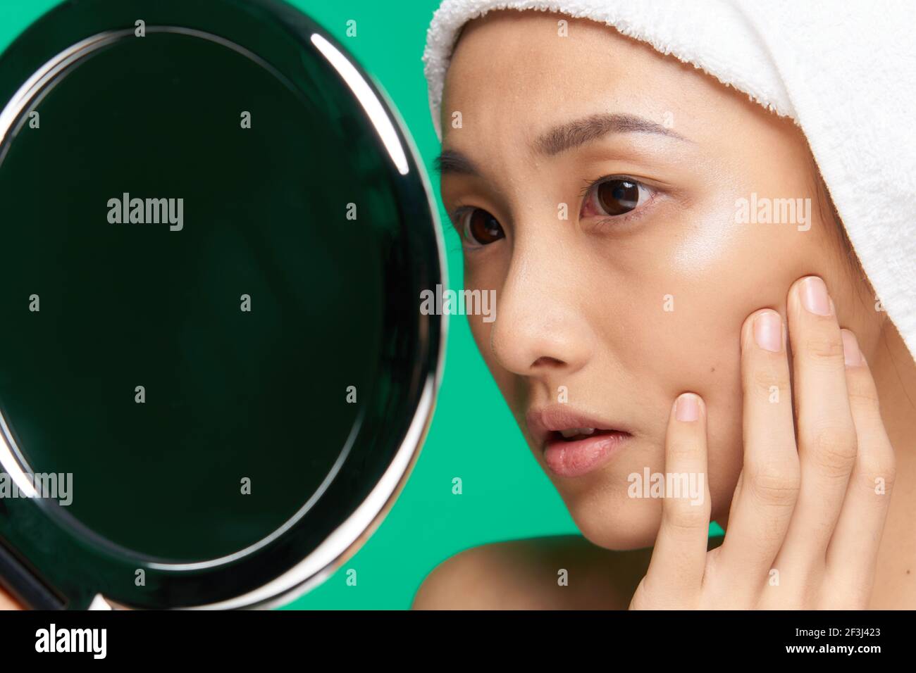 woman looks in the mirror clean skin face close up after shower Stock