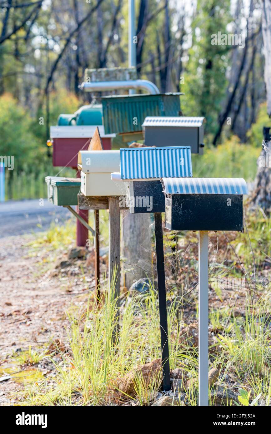 A line of letter boxes on a country road in rural NSW Australia. Letter boxes are often congregated to save time for postal workers aka Posties Stock Photo