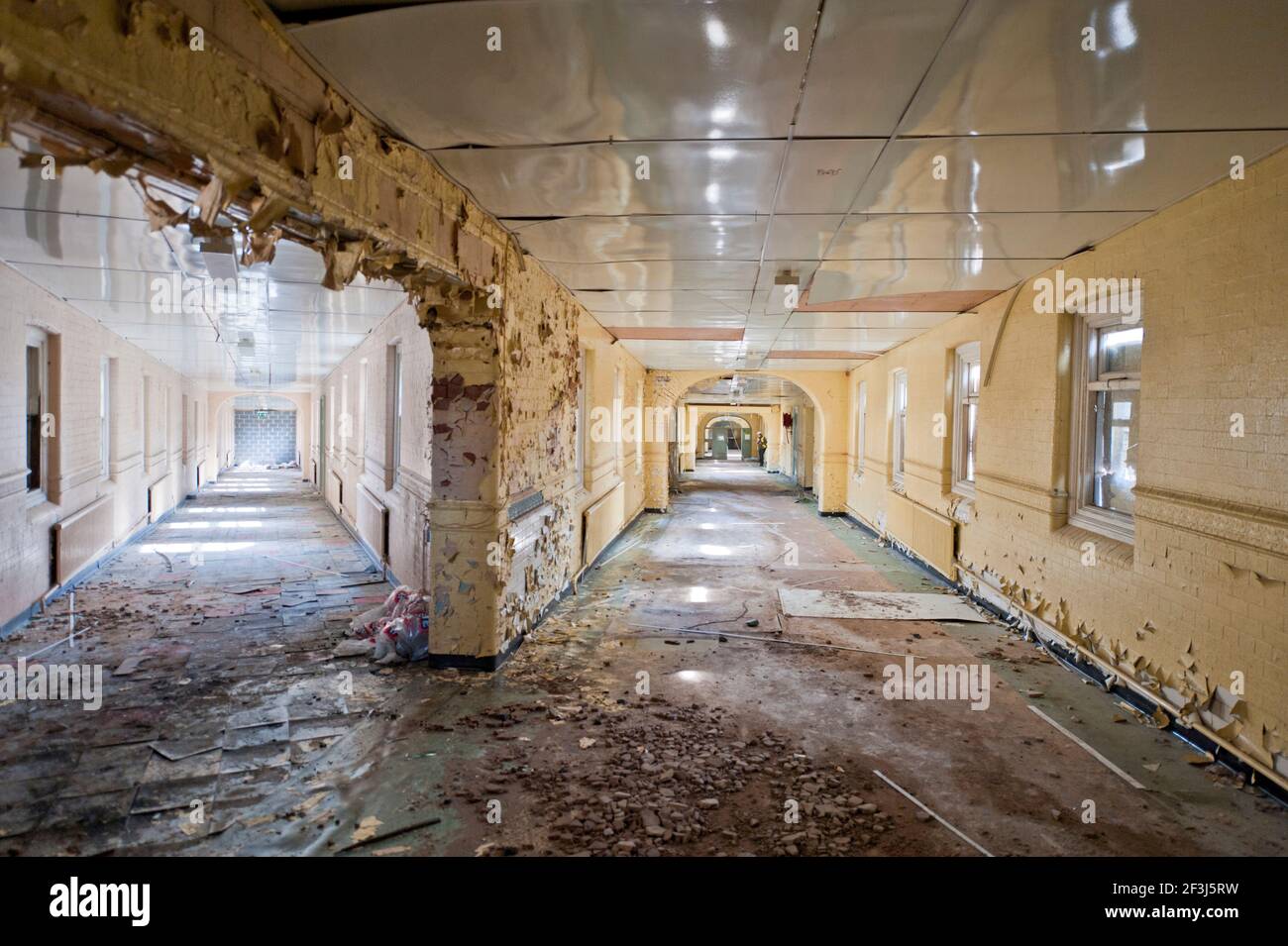 View down a V-shaped corridor with paint peeling off walls in a derelict part of the former High Royds pyshciatiric hospital in Menston, West Yorkshir Stock Photo