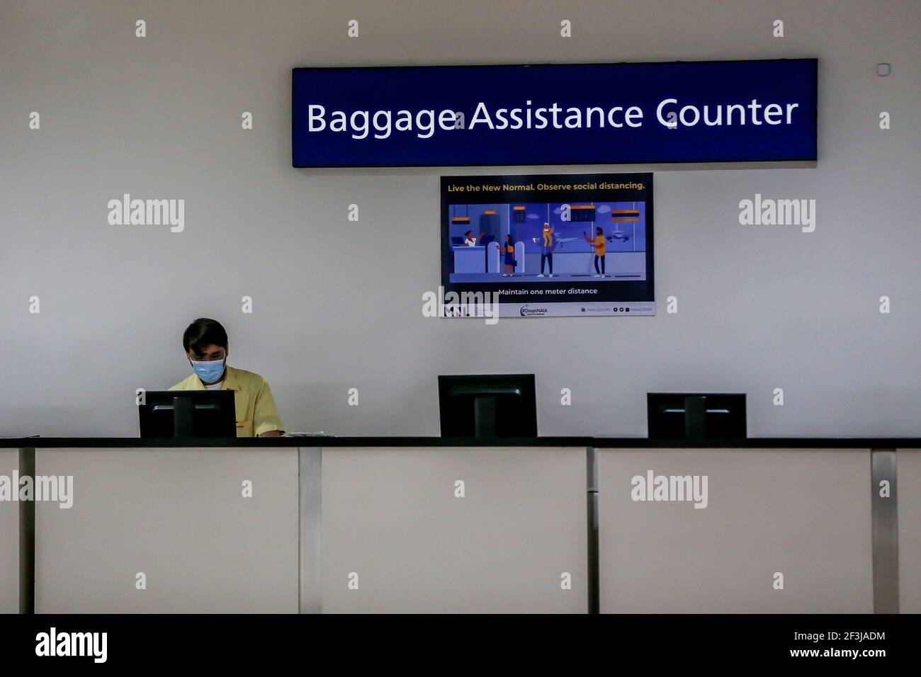 (210317) -- MANILA, March 17, 2021 (Xinhua) -- An airport employee wearing a protective mask works behind a baggage assistance counter inside the Terminal 1 of the Ninoy Aquino International Airport in Manila, the Philippines on March 17, 2021. The Philippines said it will temporarily suspend the entry of foreigners and some citizens as the Southeast Asian country battles a renewed spike in COVID-19 cases. In a statement issued on Tuesday night, the country's coronavirus task force said foreign citizens and returning nationals who had not been working overseas will not be able to enter the co Stock Photo