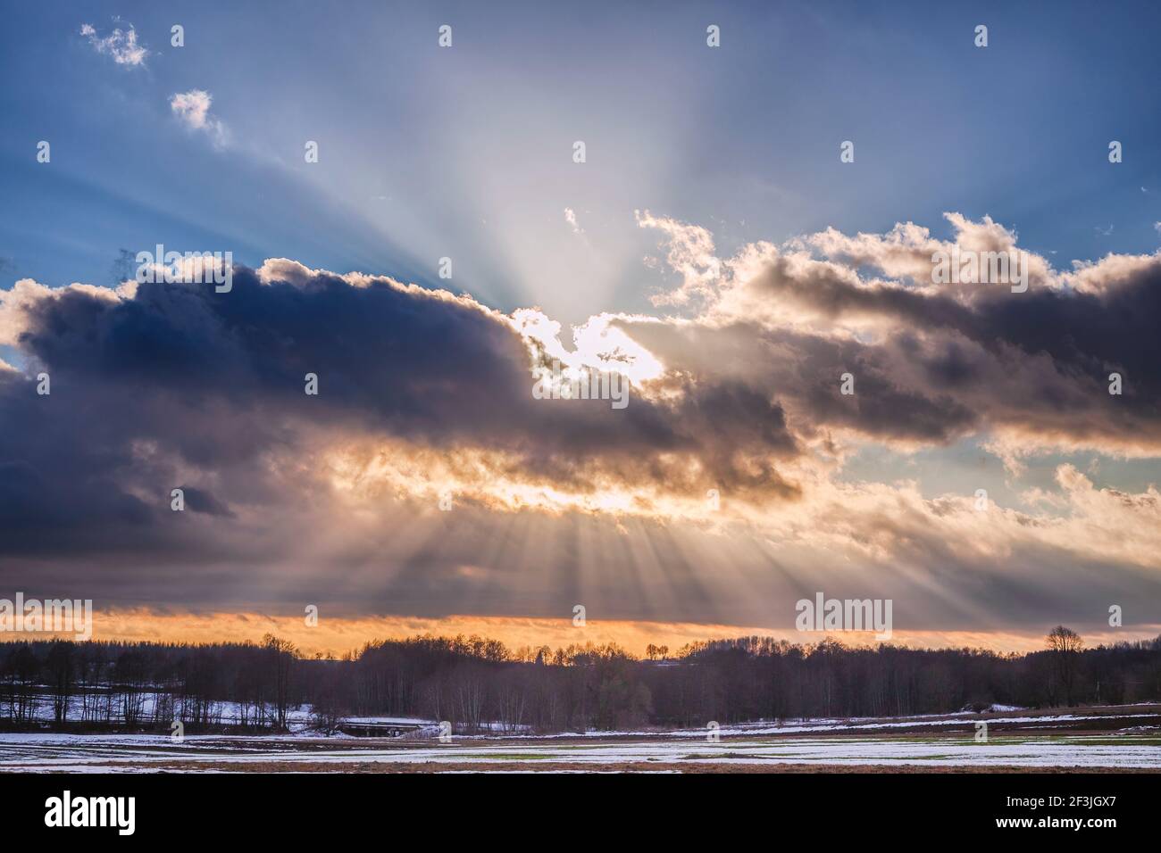 Sunset over the snowy field with sunrays Stock Photo