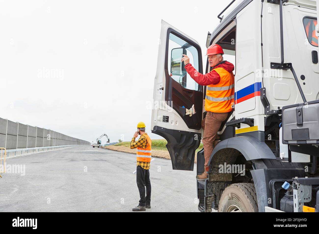 Truck drivers and construction workers on the construction site of road
