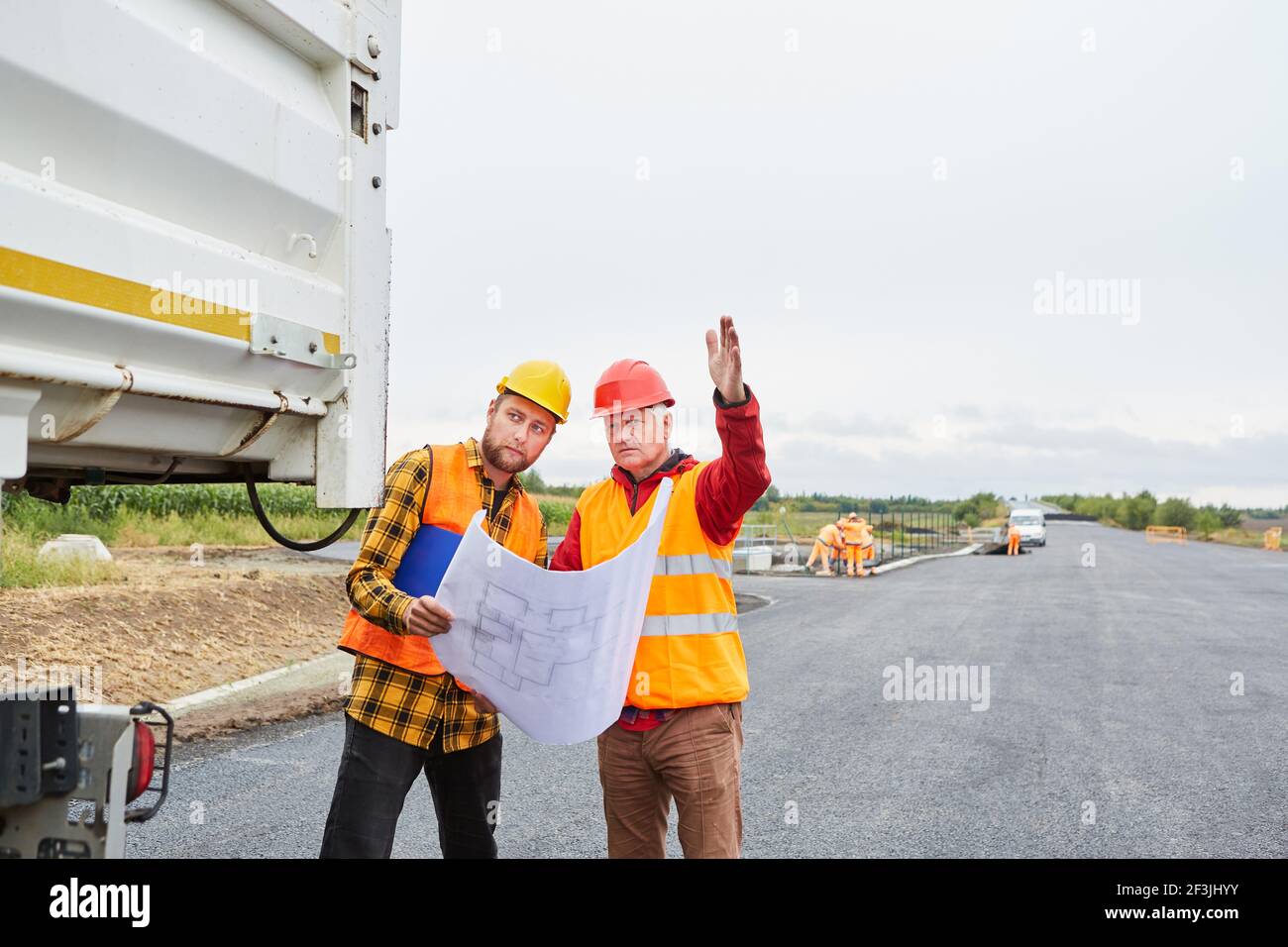 Architect and construction worker with site plan discuss development of new building area Stock Photo