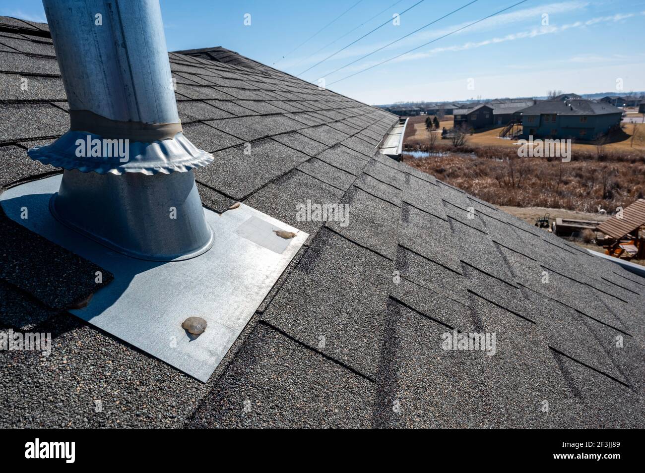 Vent on a shingle roof with silicon caulking and flashing for a water tight seal Stock Photo Alamy