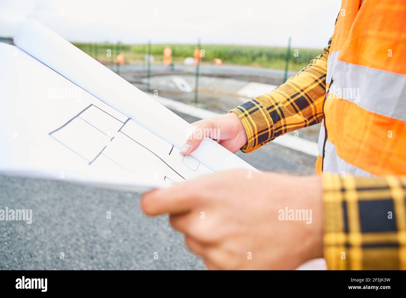 Construction worker with floor plan when planning the construction of a house in the new development area Stock Photo